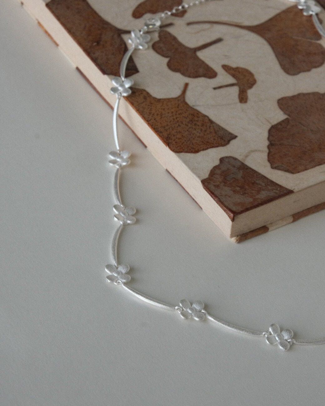 Dainty daisy chain necklace with small, polished floral links - side view - 4th - SWEEKU jewelry