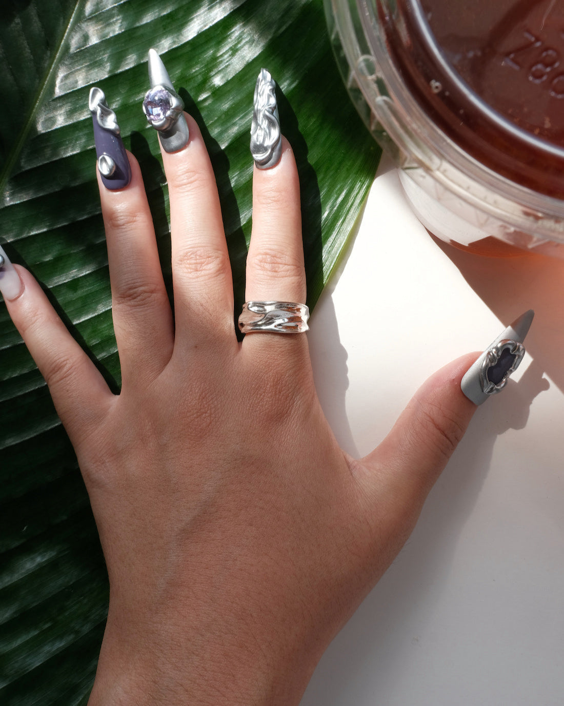 Model wearing sculptural molten metal ring with a polished, fluid design and adjustable band – top view – SWEEKU jewelry