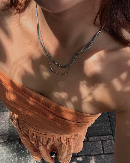 Model wearing two-layer snake chain necklace with a small, polished tear drop pendant - top view - SWEEKU jewelry