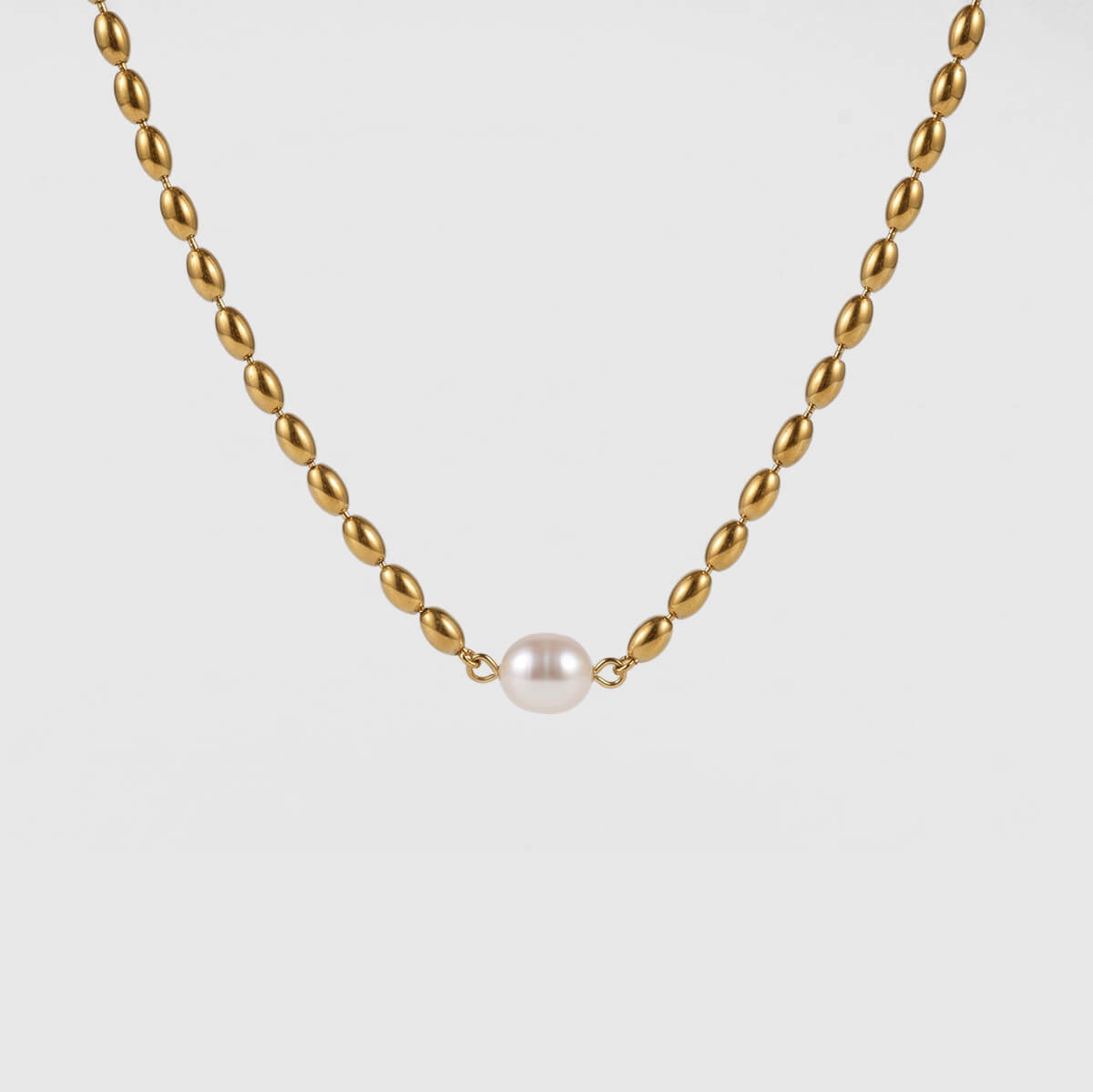 A gold chain necklace with a single white pearl pendant, centered against a light gray background.