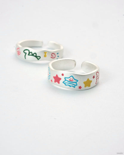 Cosmic Duo Ring Set featuring two adjustable silver enamel rings with colorful designs