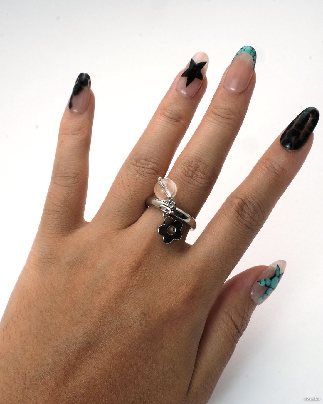 Adjustable silver open ring with flower charm and clear crystal bead accent on white background