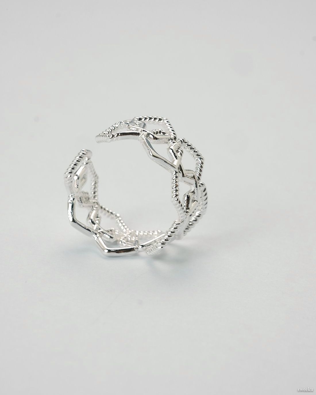 Adjustable silver geometric open lattice ring on white background