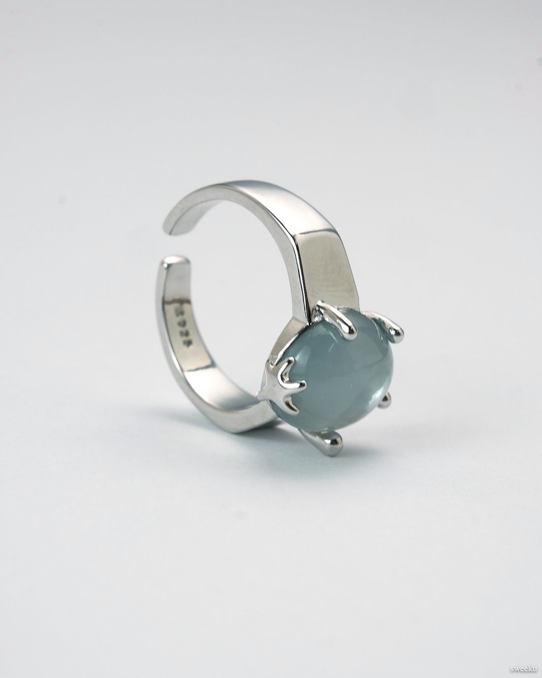Adjustable silver ring with smooth grey gemstone centerpiece on white background