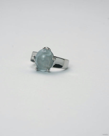 Adjustable silver ring with smooth grey gemstone centerpiece on white background