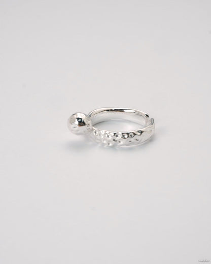 Adjustable silver molten-texture ring with a polished metal sphere accent on a white background.