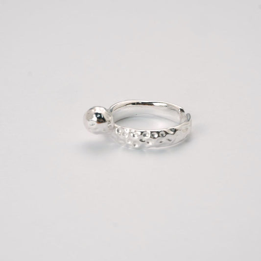 Adjustable silver molten-texture ring with a polished metal sphere accent on a white background.