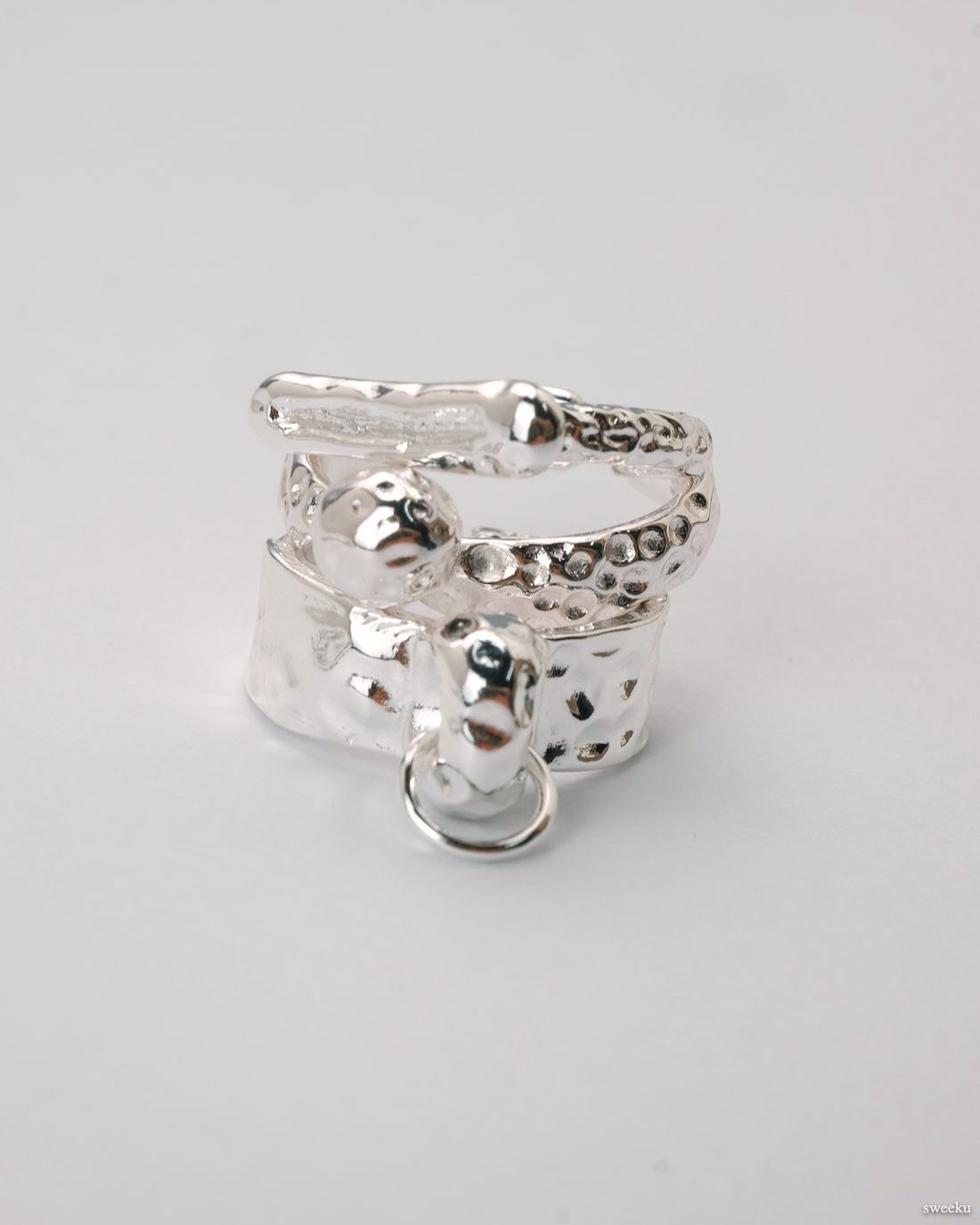 Close-up of adjustable molten-texture silver ring trio styled on fingers.