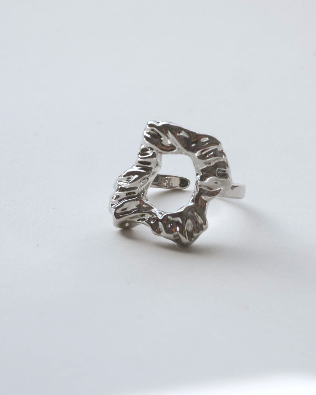 Front view of abstract molten sculptural ring with a polished, fluid design and adjustable band

