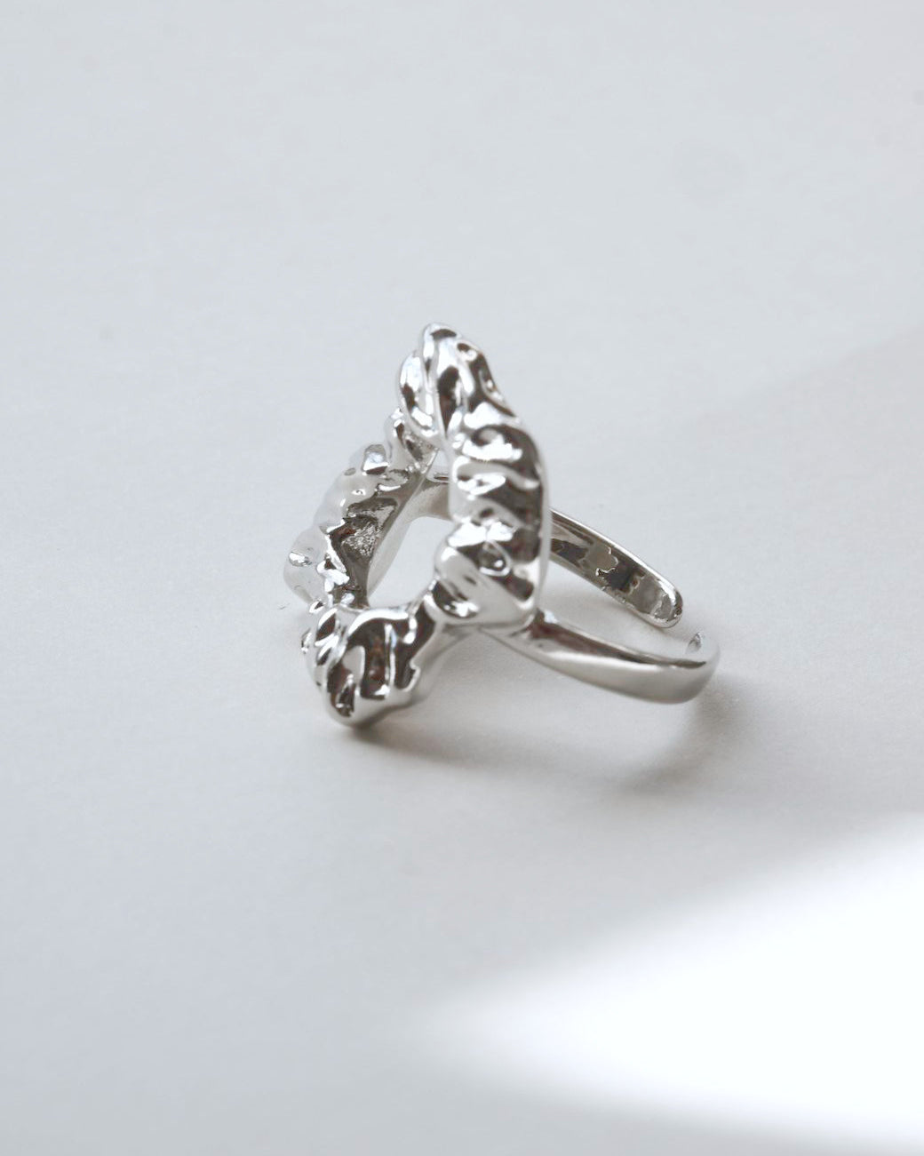 Side view of abstract molten sculptural ring with a polished, fluid design and adjustable band