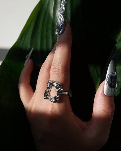 Side view of wearing of abstract molten sculptural ring with a polished, fluid design and adjustable band
