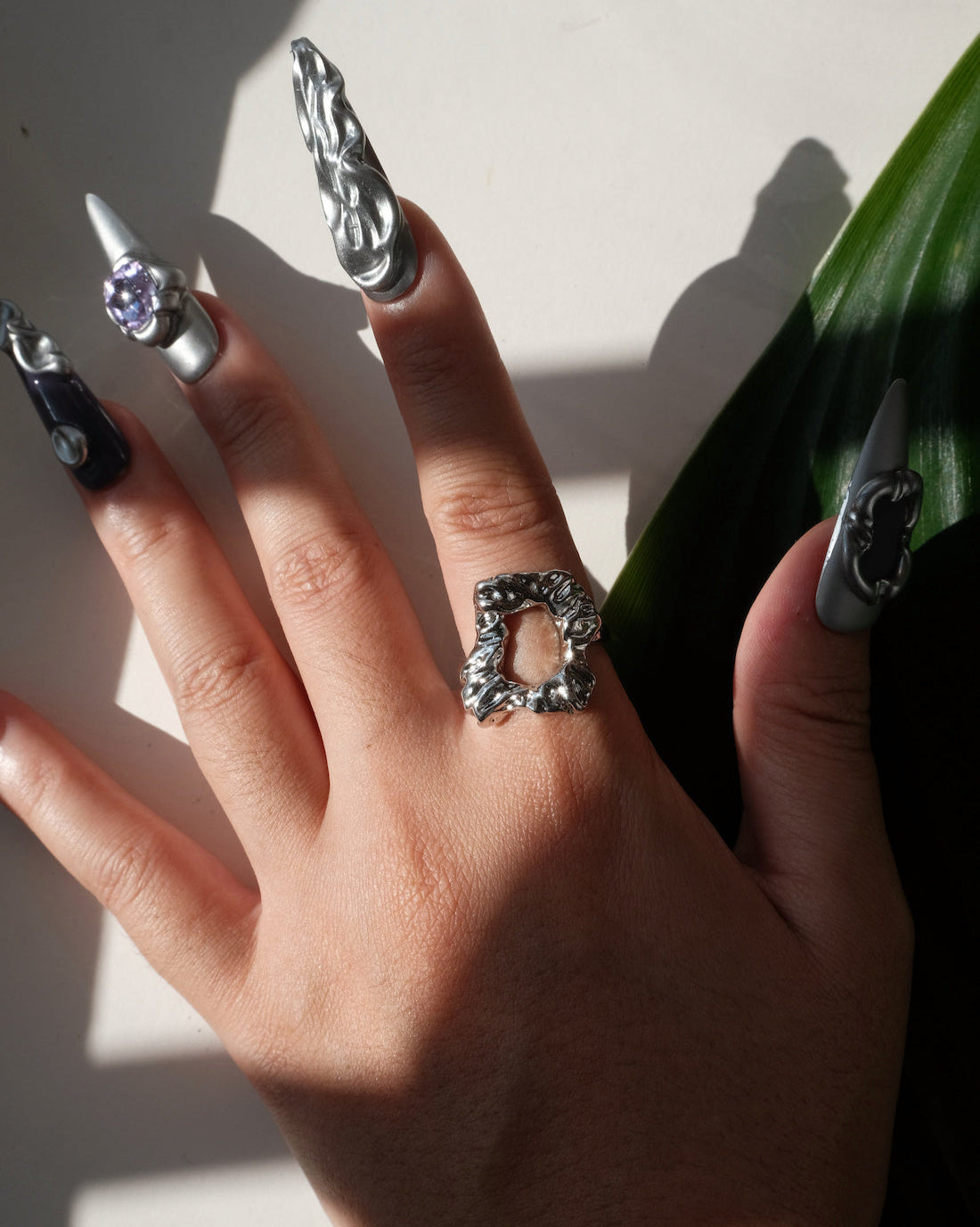 Top view of wearing of abstract molten sculptural ring with a polished, fluid design and adjustable band
