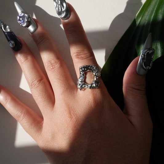 Top view of wearing of abstract molten sculptural ring with a polished, fluid design and adjustable band
