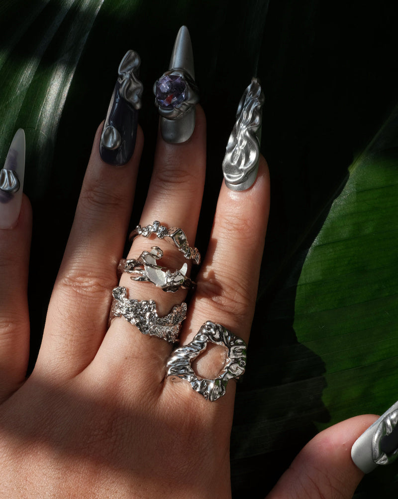 Wearing down view of abstract textured sculptural ring with a wide, fluid design and adjustable band
