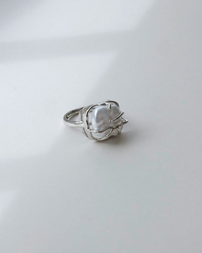 Side view of a baroque pearl cage ring showing the unique setting and irregular white pearl