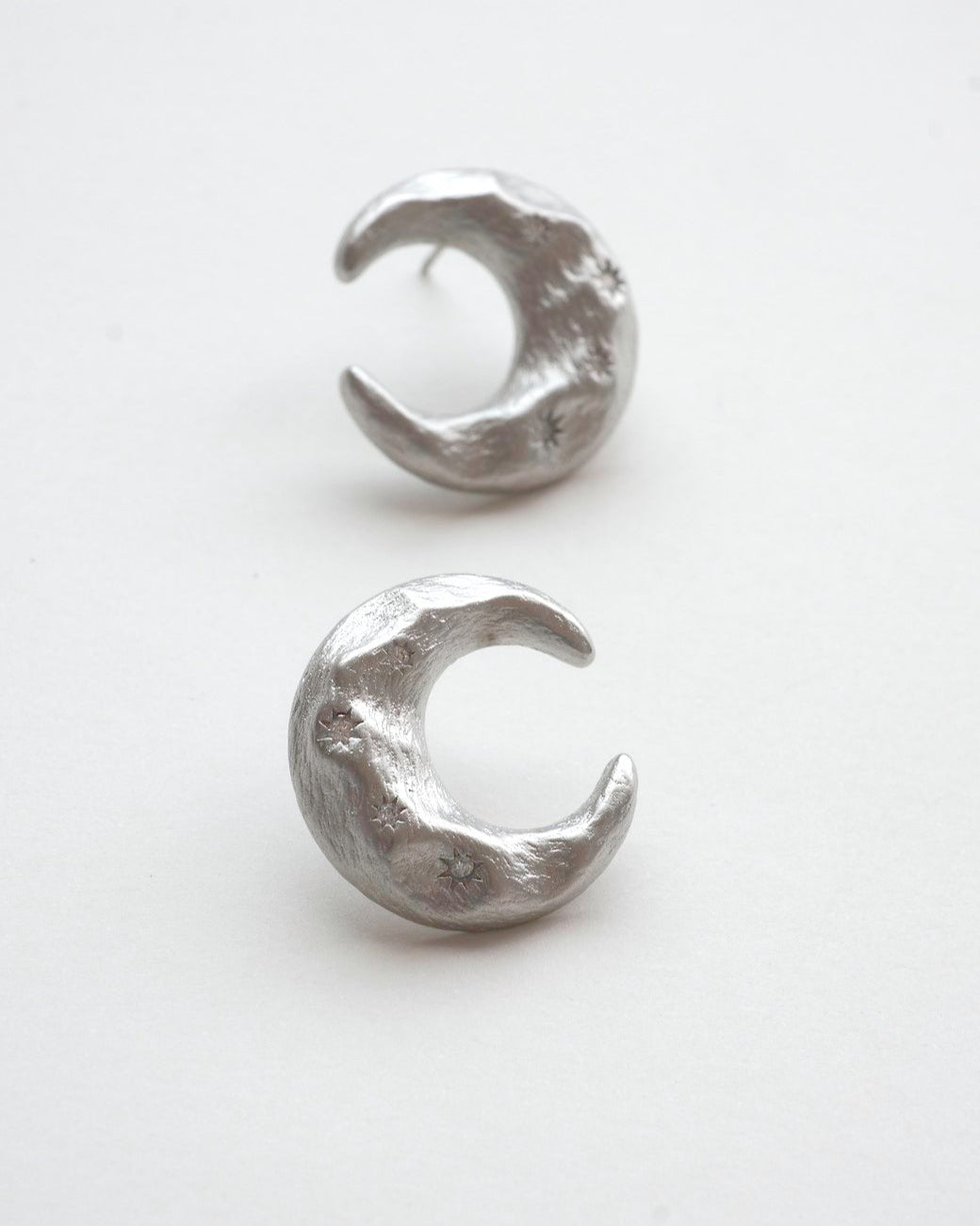 Pair of celestial crescent moon stud earrings crafted from textured copper with embedded stars and silver posts – front view – SWEEKU jewelry