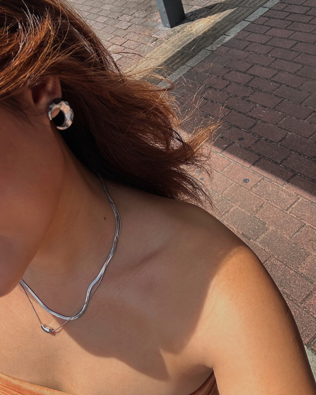 Model wearing pair of celestial crescent moon stud earrings crafted from textured copper with embedded stars and silver posts – side view – SWEEKU jewelry