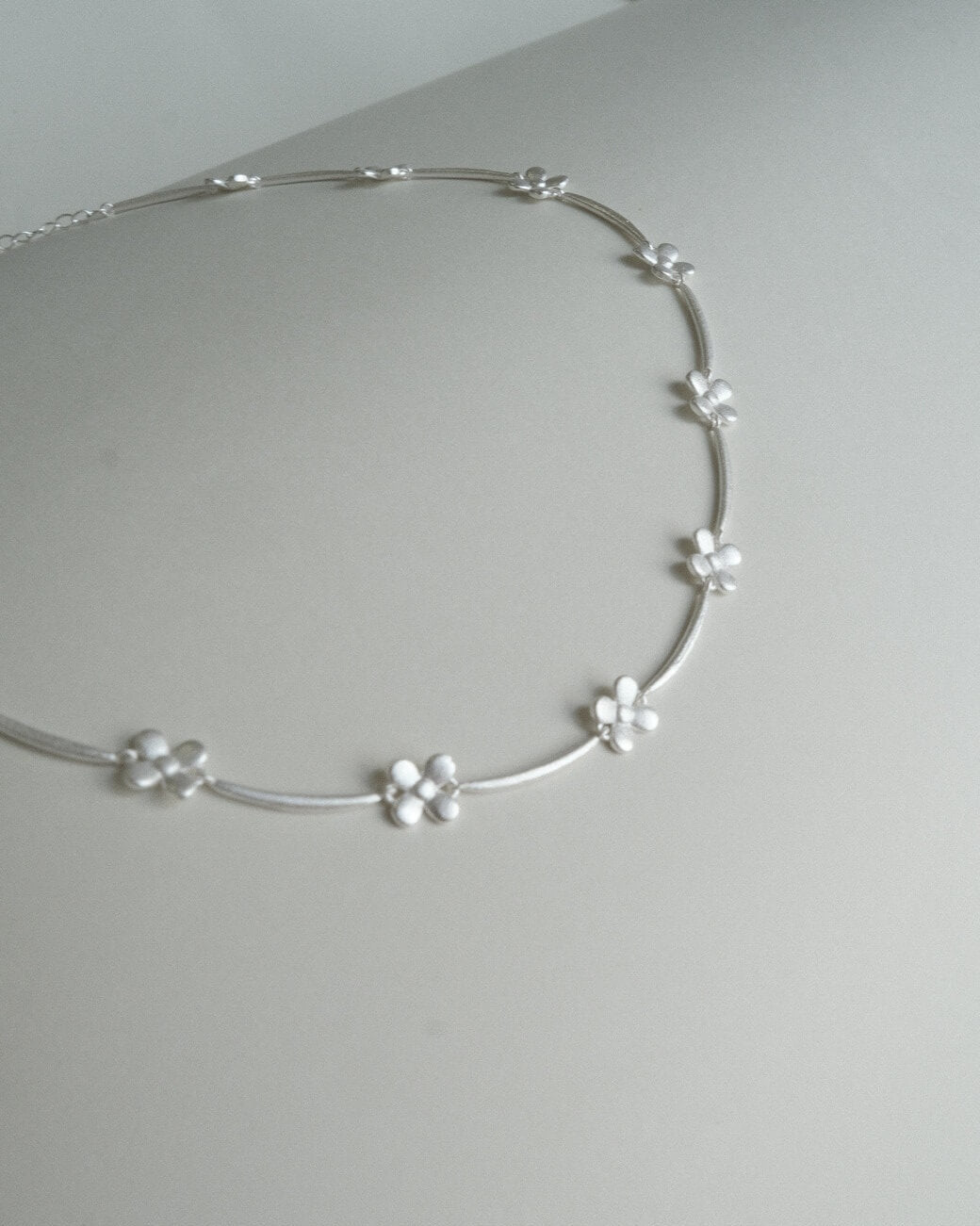 Dainty daisy chain necklace with small, polished floral links - detail - front view - SWEEKU jewelry