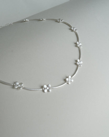 Dainty daisy chain necklace with small, polished floral links - detail - front view - SWEEKU jewelry