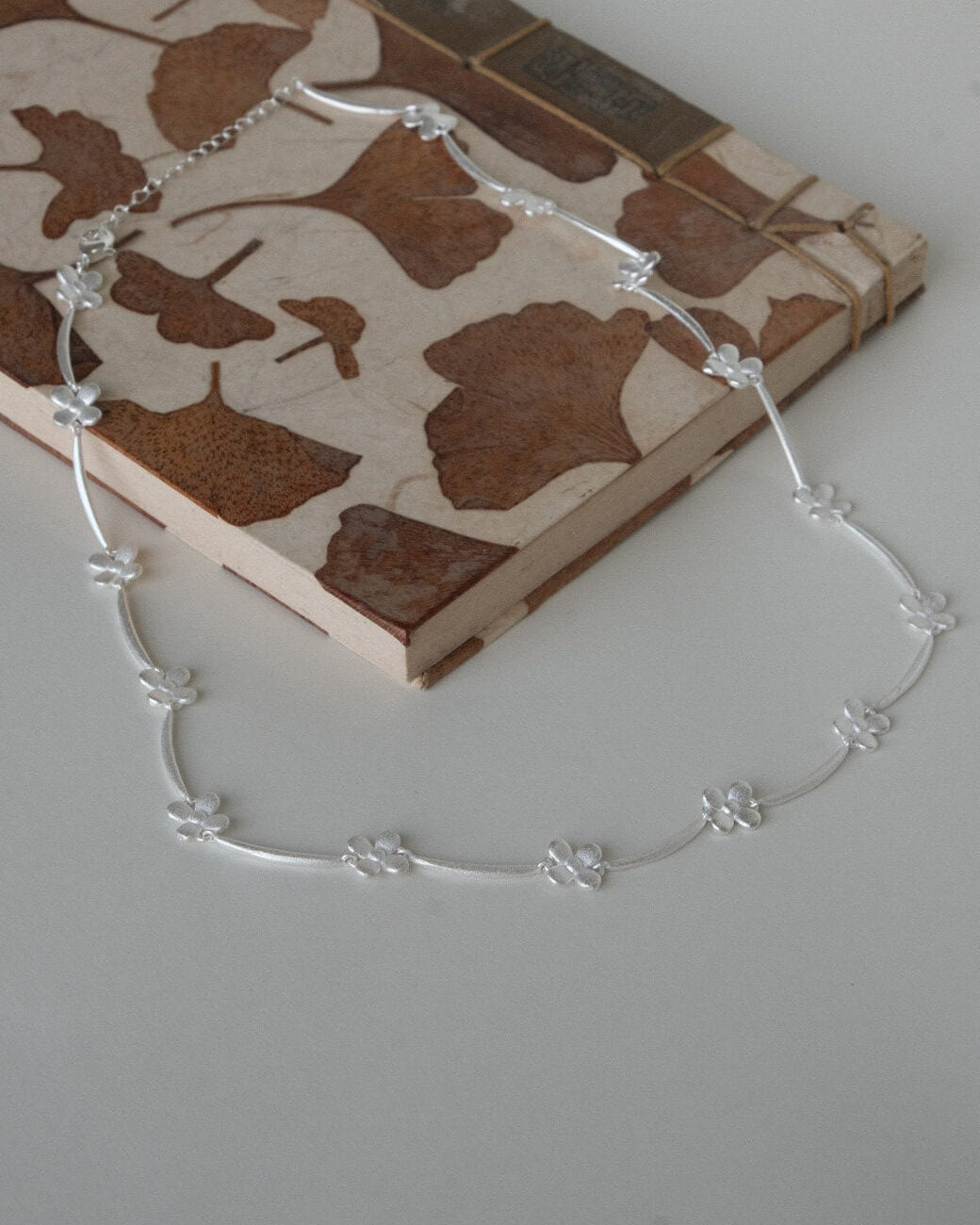 Dainty daisy chain necklace with small, polished floral links - side view - 2nd- SWEEKU jewelry