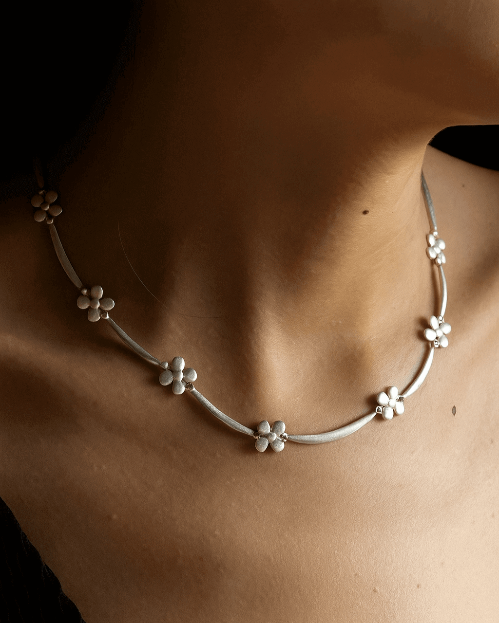 Model wearing dainty daisy chain necklace with small, polished floral links - side view - SWEEKU jewelry