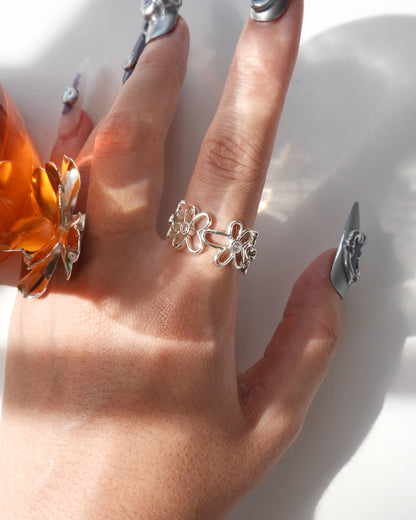 Wearing front view of dainty flower adjustable ring with an open band and clear crystal accents