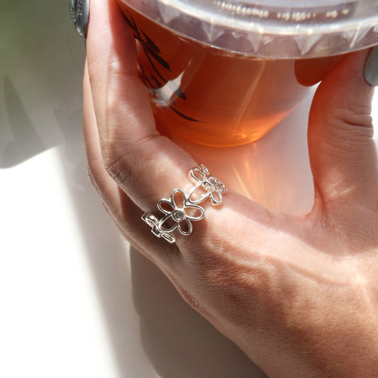 Wearing side view of dainty flower adjustable ring with an open band and clear crystal accents