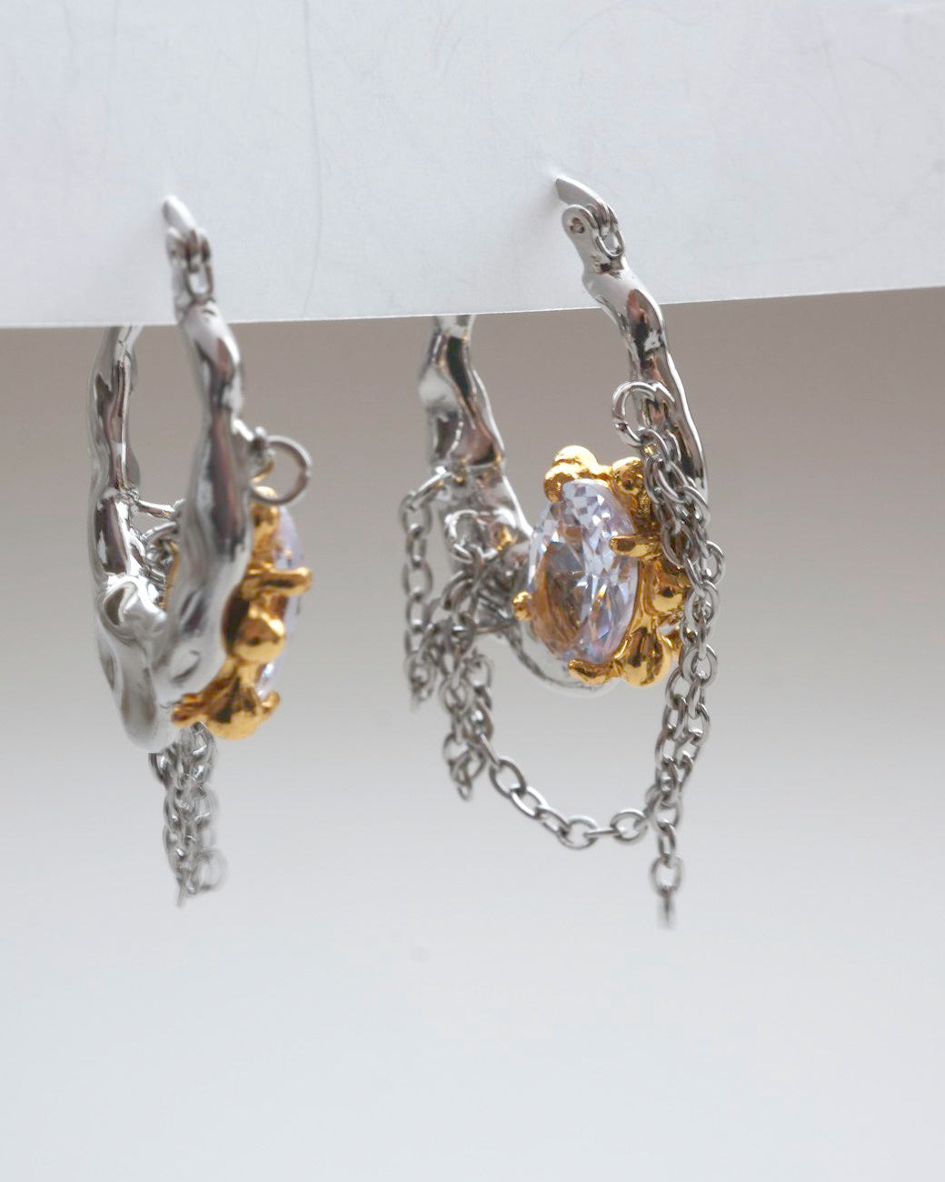 Pair of unique melting metal two-tone copper hoop earrings with dangling chains and an oval crystal - side view - SWEEKU jewelry
