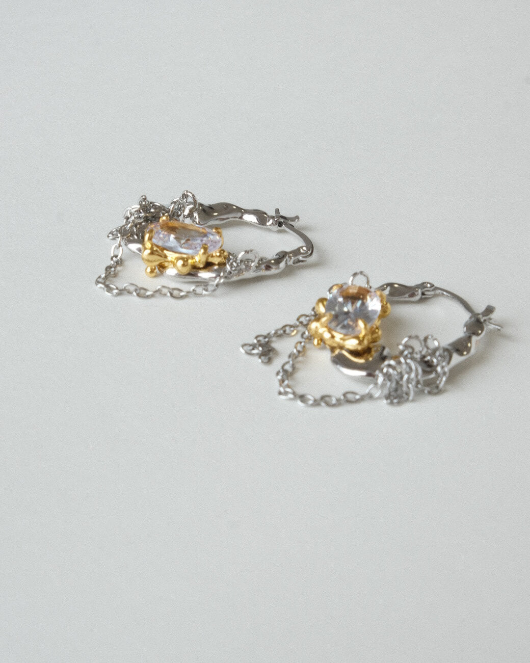 Pair of unique melting metal two-tone copper hoop earrings with dangling chains and an oval crystal - side view 2 - SWEEKU jewelry