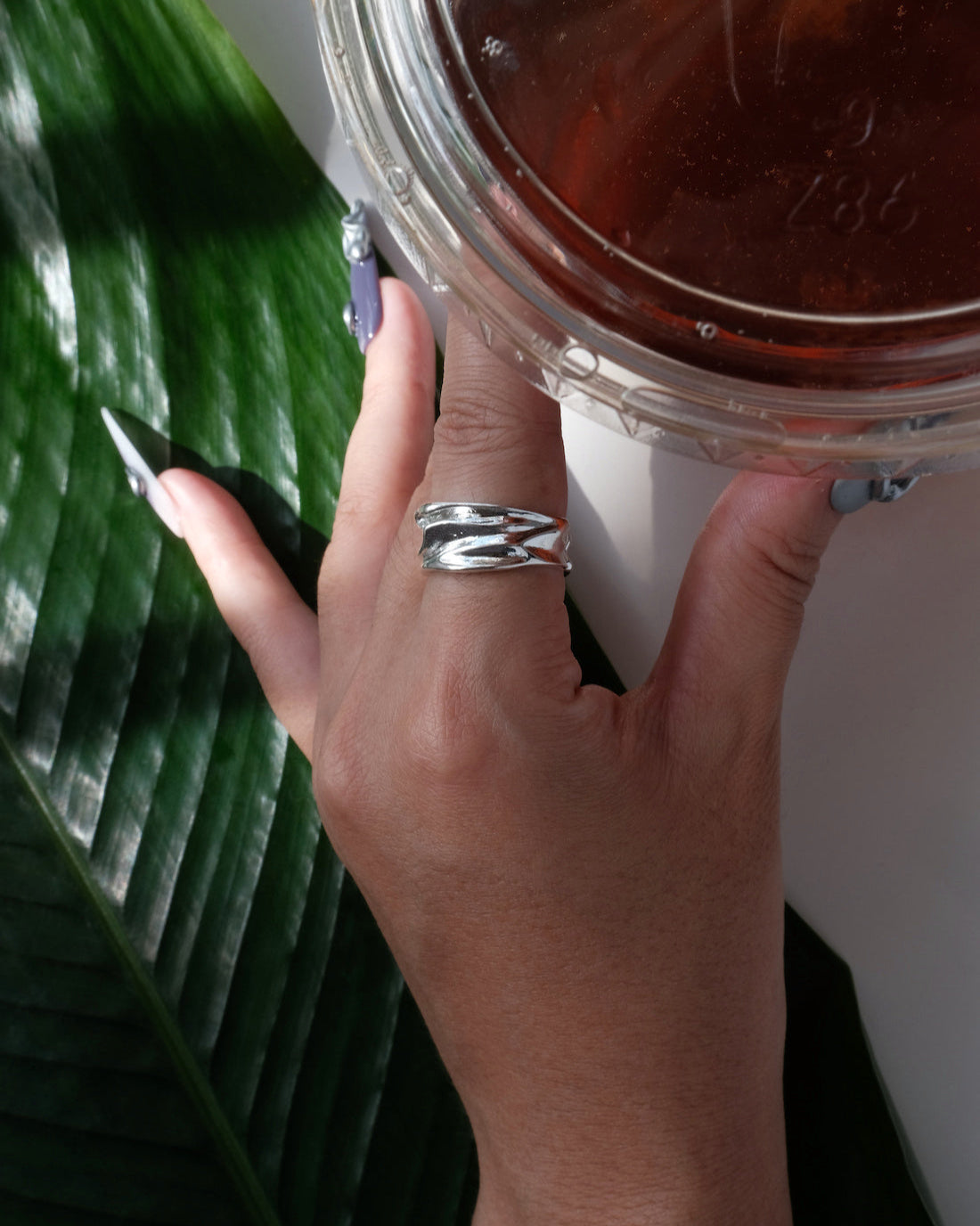 Model wearing sculptural molten metal ring with a polished, fluid design and adjustable band – side view – SWEEKU jewelry
