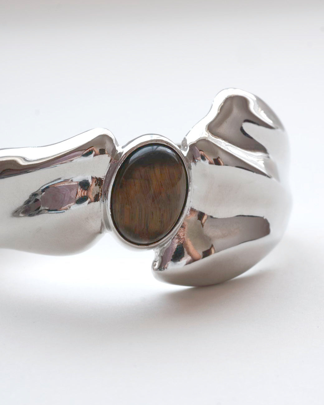 Sculptural liquid metal cuff bracelet with a polished finish and a central Tiger's Eye gemstone – front view detail – SWEEKU jewelry
