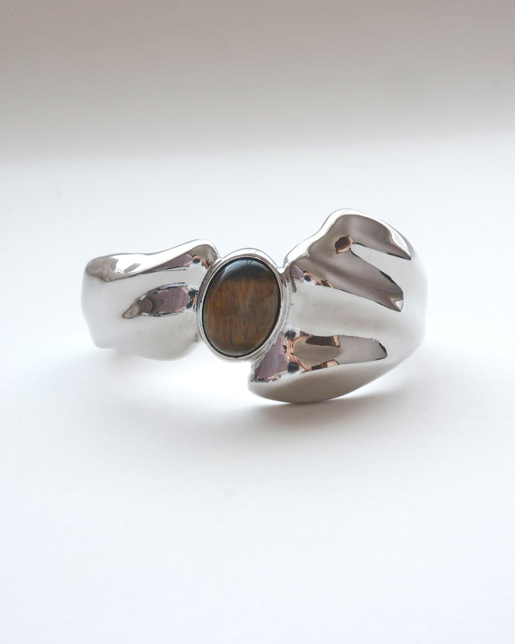 Sculptural liquid metal cuff bracelet with a polished finish and a central Tiger's Eye gemstone – front view – SWEEKU jewelry