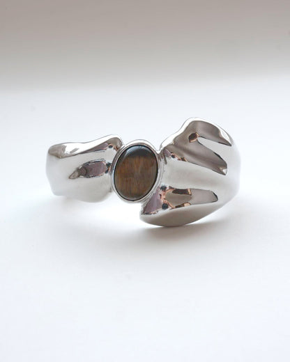 Sculptural liquid metal cuff bracelet with a polished finish and a central Tiger's Eye gemstone – front view – SWEEKU jewelry