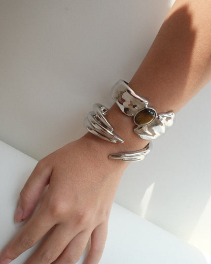 Model wearing sculptural liquid metal cuff bracelet with a polished finish and a central Tiger's Eye gemstone – front view – SWEEKU jewelry