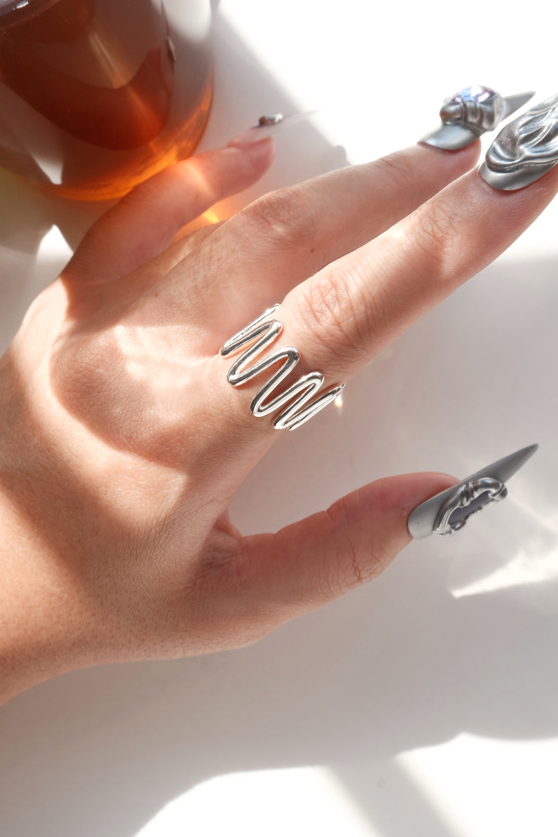 Side view of wearing of sculptural wavy line ring with a polished, fluid design and adjustable band
