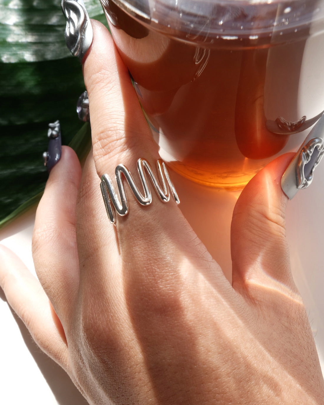 Wearing side view of sculptural wavy line ring with a polished, fluid design and adjustable band